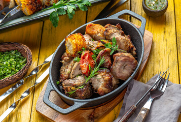 Bbq grilled meat - pork, chicken and vegetable on cast iron pan. Grilled skewers on yellow wooden background. Top view