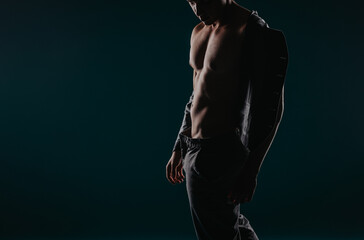 Fototapeta na wymiar Fit Man Showing Muscles in Powerful Studio Silhouette