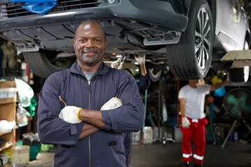 mechanic smiling and folded arms pose in automobile repair shop