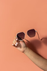 hand with sunglasses with pink background