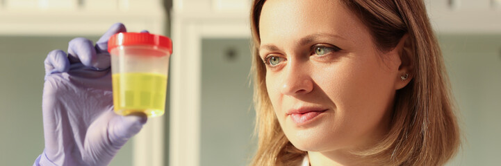 Concentrated woman looks at urine sample in container