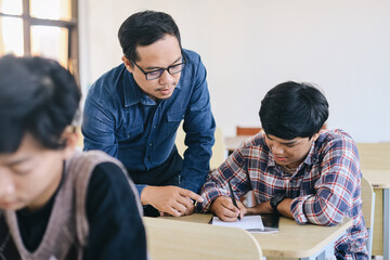 Fototapeta premium Teacher helping male student with assignment in the classroom