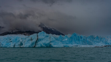 The beautiful blue glacier Perito Moreno rises above the turquoise lake. A wall of ice with cracks,...