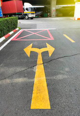 Directional arrows outside an industrial building painted yellow between parallel yellow lines on...
