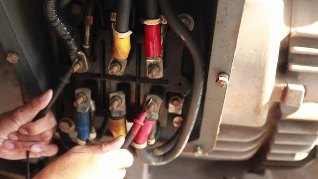 Stop checking the motor repairs : Closeup male electrician worker uses multimeter to check motor abnormalities 125 HP and measure electrical current at electric motor wiring terminals for safety.