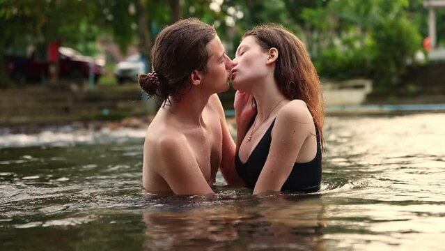 Happy romantic couple having vacation traveling in summer in nature and staying at a happy resort playing water in the stream standing kissing and hugging each other having the utmost 