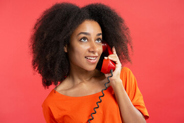 Beautiful authentic African American woman holding red handset, call looking away - obrazy, fototapety, plakaty
