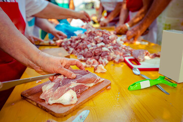 Elderly man and several women are cutting are cutting meat