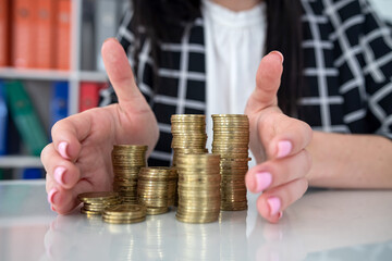 Closeup of business woman putting cent on stack of coins on the office table