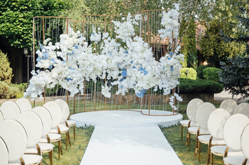 Luxury white-golden chairs on wedding ceremony outdoors. Festive decorations. Empty rows armchairs for guests.