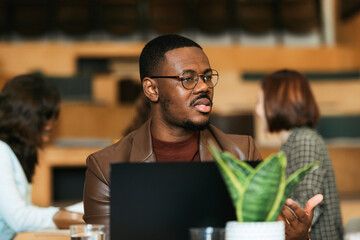 Young and handsome businessman working on his laptop and explaining something