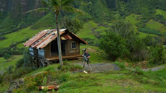Man Setting Up Tripod In Front Of Old Shack In Hawaiian Valley