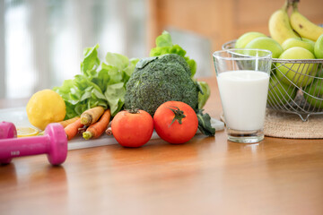 Glass of milk, fruit juice blender, vegetables and fruits prepared on a wooden table for a healthy breakfast, healthy foods on the table in the kitchen