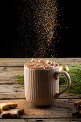 Vertical image of chocolate pouring over mug of chocolate and christmas decorations with copy space