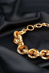 Gold chain on black silk fabric background