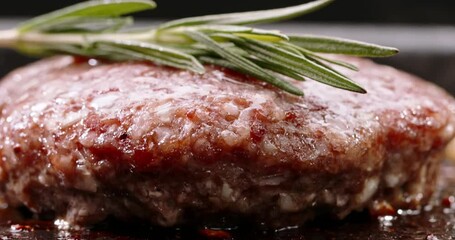 Beef cutlet for halal burger fried in frying pan. Sprig of rosemary placed on cutlet during frying. Cinematic advertisement video burger cooking. Close-up of delectable cutlets frying to perfection