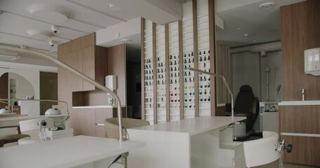 Spacious nail studio with workplace for manicure procedure and pedicure zone. Beauty salon with minimalist interior white tables, comfort chairs and modern equipment.