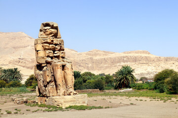 One of the famous Colossi of Memnon, Valley of Kings, Luxor, Egypt. Ancient stone statue of Pharaoh Amenhotep III in Theban Necropolis