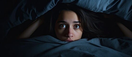 Insomniac young woman in bed eyes open troubled by nightmares With copyspace for text