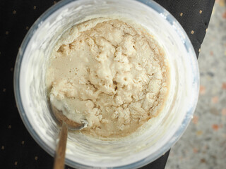 top view mixing flour, water and sourdough bread starter in plastic food container