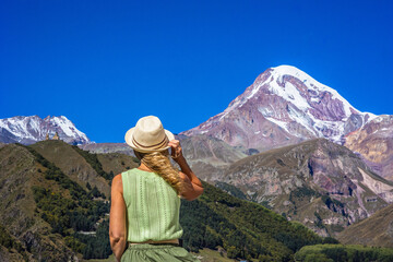 Fototapeta na wymiar girl traveler enjoying the picturesque view Mount Kazbek. Travel in Georgia