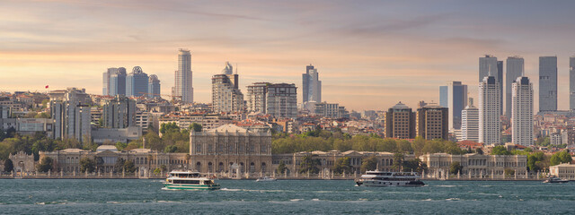 Naklejka premium Stunning view of the city of Istanbul, Turkey from across the Bosphorus strait. The image captures the beauty of the city's skyline, with its iconic buildings including Dolmabahce Palace before sunset