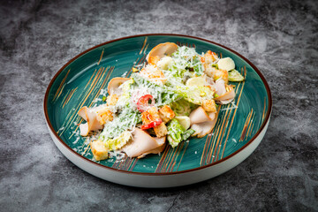 side view of caesar salad with cheese on a blue plate