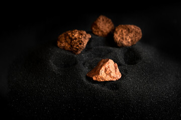 Lumps of pure copper or pink gold ore on a black sand background - obrazy, fototapety, plakaty