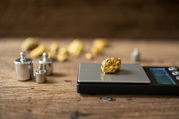 pure gold ore from a mine is placed on a weighing scale for evaluation. - obrazy, fototapety, plakaty