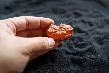 Man's hand holding a piece of copper to examine it for industrial use on white background