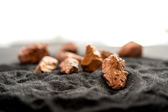 Lumps of pure copper or pink gold ore on a black sand background