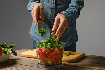 Close up view of female hands dropping chopped cilantro into blender