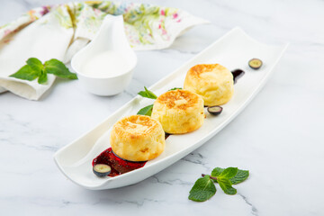 lush and tall cheesecakes with jam and mint on a white plate side view