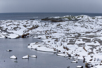 Norway and Lofoten Travel Concepts. Snowy and Stony Lofoten Islands Seascape in Norway Evenly Covered with Snow.