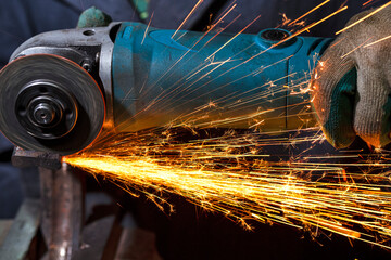 Extreme Closeup of Hands of Fitter in Protective Gloves and Uniform With Gringer Tool For Metal Work With Bunch of Sparks