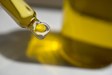 A drop of cosmetic aromatic oil drips from the pipette. Front view.