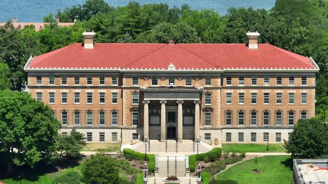Aerial view of a historic brick building with a red tiled roof, nestled among lush green trees on the University of Wisconsin campus. UW College of Agricultural and Life Sciences.