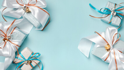 Gift boxes wrapped in blue, white and silver paper with white, blue and gold ribbon bows. Blue background, top view. Christmas and New Year gifts, Boxing Day.