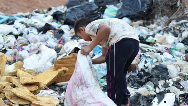 A poor child collects trash to sell. Among the piles of dirty garbage. Recycling concepts. child labor and poverty.