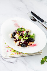salad of blackberries, beets, seeds and cheese, side view on a white plate
