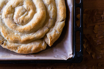 Homemade turkish greek snail roll pie on grey paper on baking pan close-up selective focus