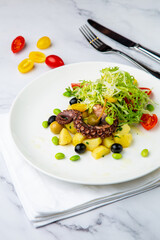 salad with olives, herbs, cherry tomatoes, potatoes and octopus tentacles side view
