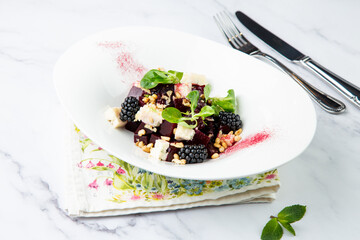 salad of blackberries, beets, seeds and cheese, side view on a white plate