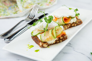 canapes on black bread with cheese, red fish, herbs and cucumber side view