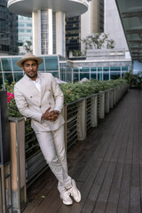 An attractive groom at an international wedding in a light suit with dark skin against the backdrop of the modern city of Singapore. His confident posture gives the impression of a strong individual.