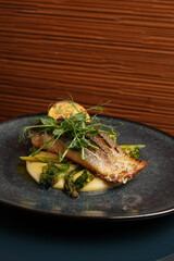 Fried dorado fish and mashed potato on a black plate