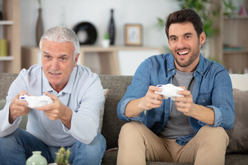 two men sitting on the sofa and playing video games
