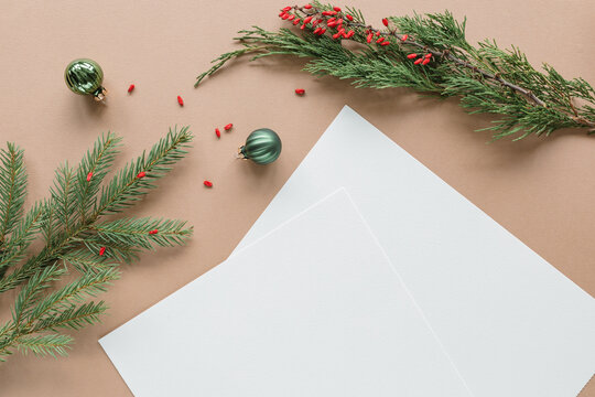 Two blank pieces of paper on a table with Christmas baubles and fir branches