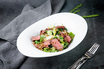 salad with pieces of beef, pistachios, lettuce and cheese side view