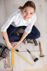 happy young woman measuring and marking laminate floor tile